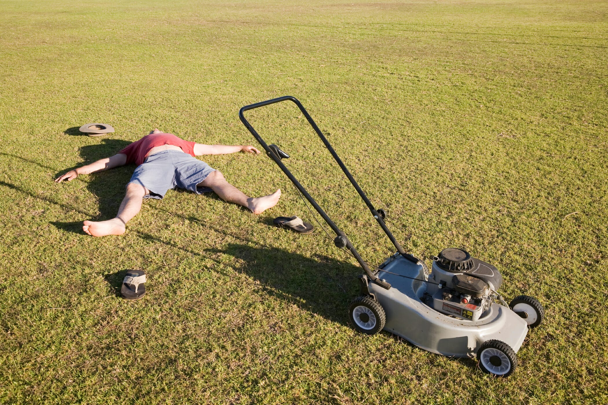 An exhausted man lying on the ground collapsed after mowing a huge lawn.